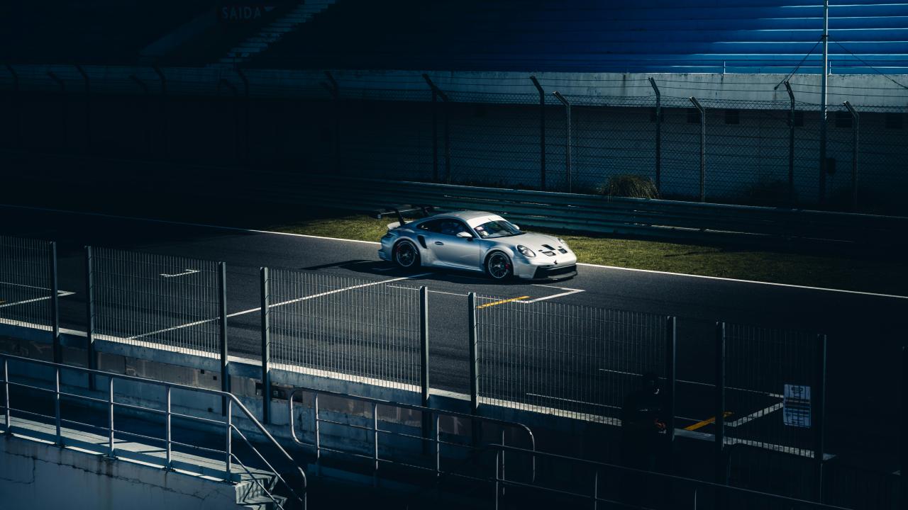 Sebuah mobil sport perak duduk di trek.
