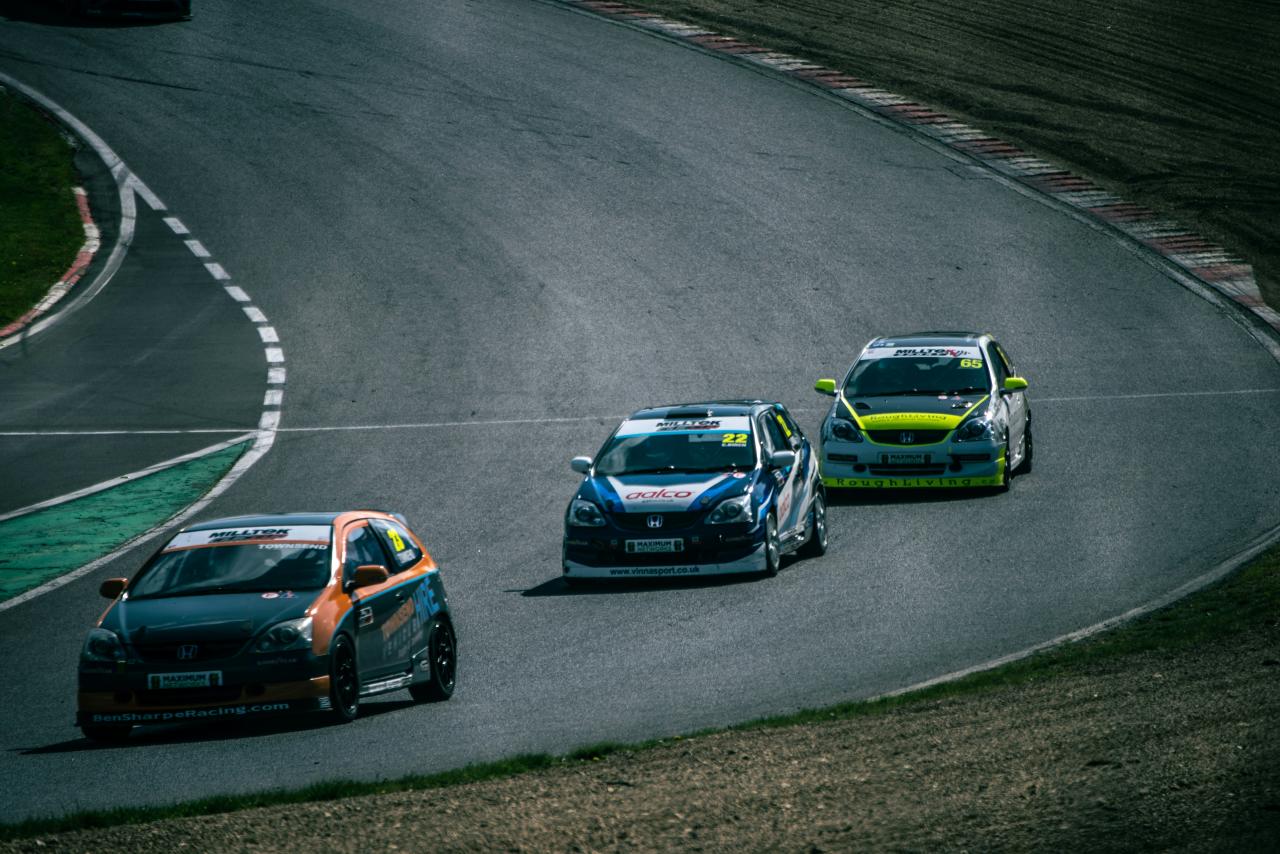 Tiga mobil balap bersaing di trek berkelok-kelok.